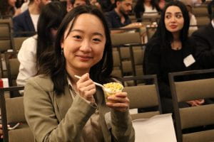 A person in the audience enjoying a cup of macaroni salad.